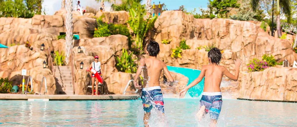 Kids splashing and running through Loews Sapphire Falls Resort pool area