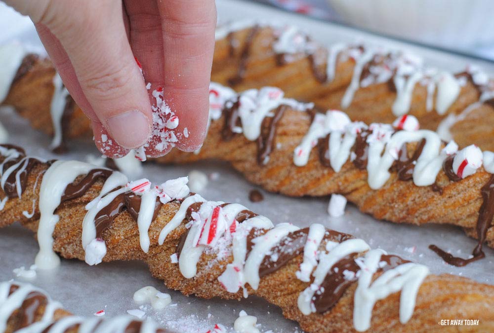 sprinkling candy canes on top of churros