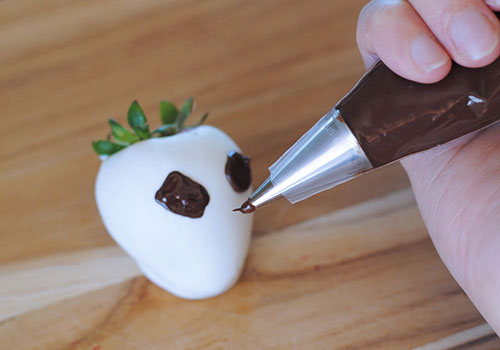 Drawing the face on Jack Skellington chocolate covered strawberries